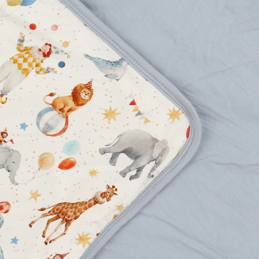 Baby blanket with circus-themed design featuring animals and stars on a light blue background.