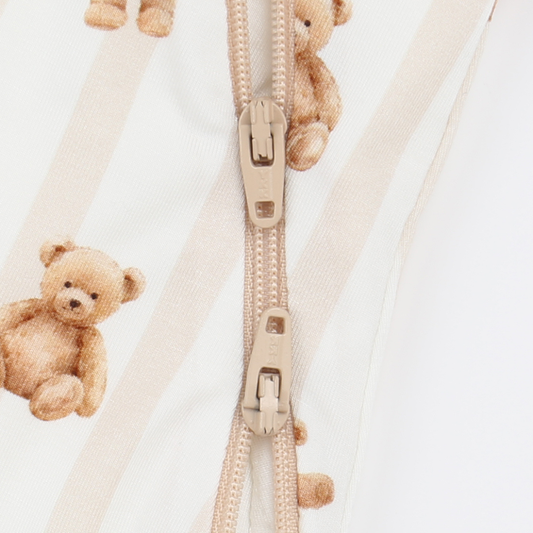 Close-up of a beige zipper with teddy bear decorations on a white background