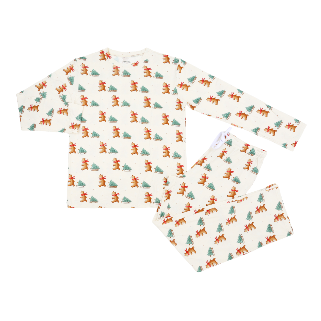 A two-piece long-sleeve pajama set featuring an off-white background with a repeating pattern of brown reindeer and green pine trees, laid flat on a white background.
