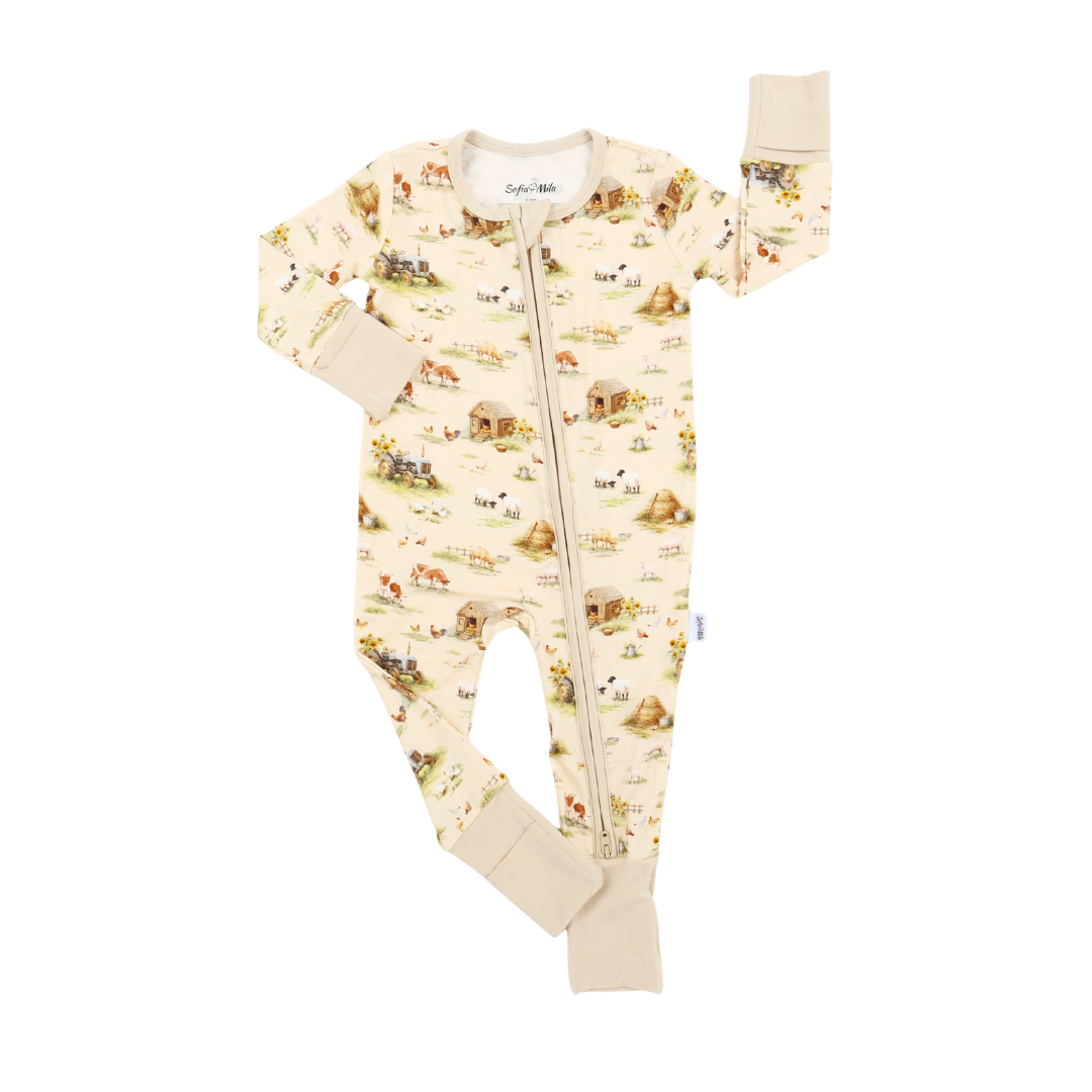 A baby long-sleeve footed sleeper in cream with a detailed safari animal and landscape print, featuring a front zipper and ribbed cuffs and footy.