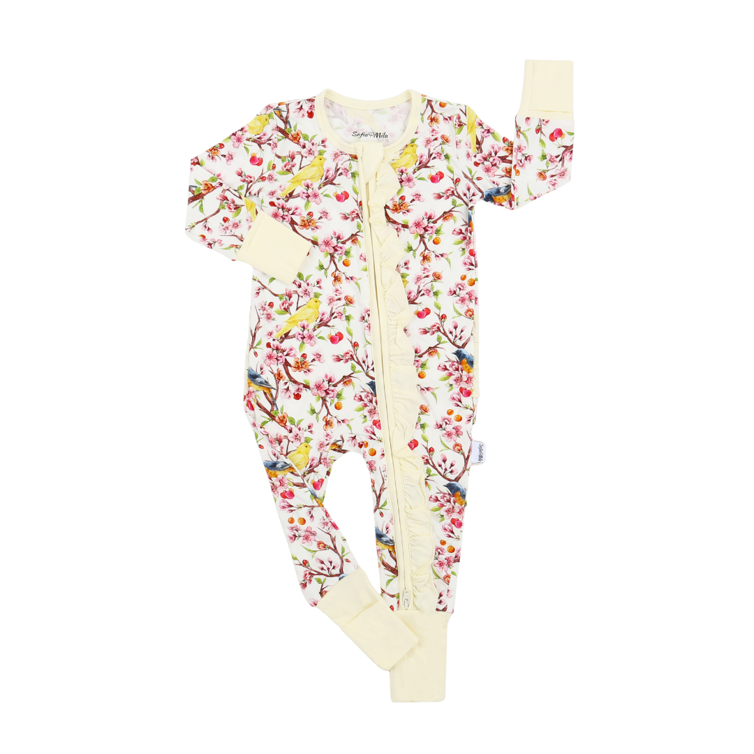 A baby long-sleeve footed sleeper with a colorful floral and bird print on a cream background, featuring a front zipper and solid cream cuffs and collar.