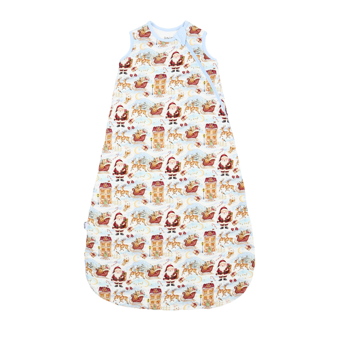 A baby sleep sack with a festive Santa Claus and reindeer print on a white background, featuring a light blue collar and shoulder straps.