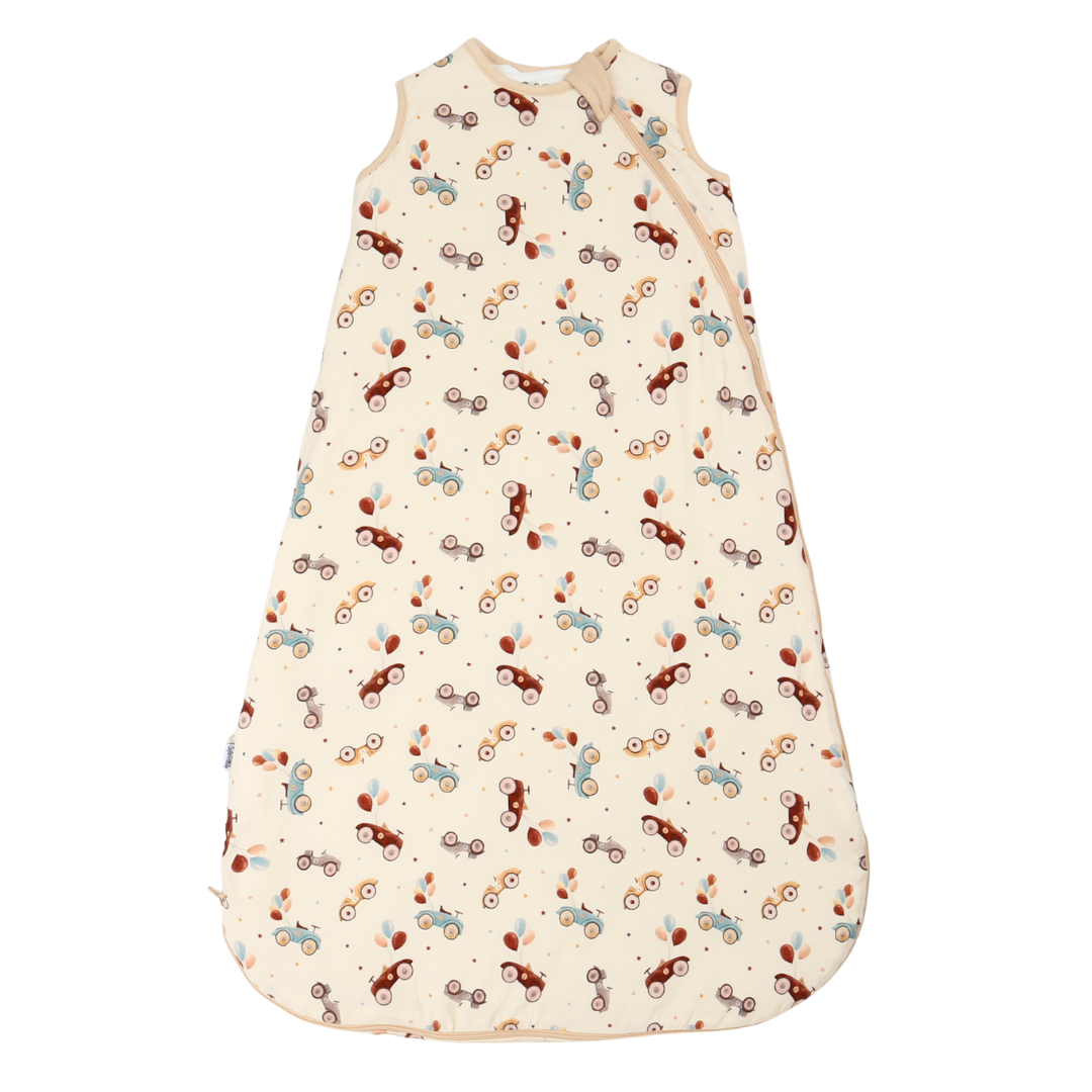 A baby sleep sack with an all-over bicycle print on a cream-colored background. The print features bicycles in brown, light blue, and dark red, with small scattered dots.