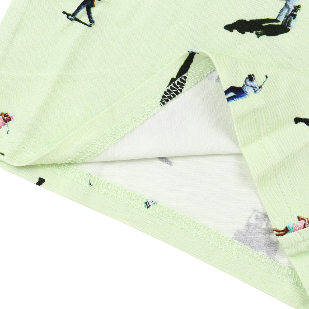 A close-up of a light mint green fabric product, likely a blanket or towel, featuring a playful all-over print of skaters and rollerbladers. The fabric is folded to show both the printed exterior and the clean white reverse side.