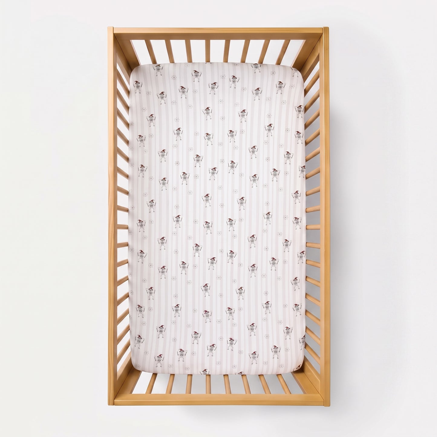 A fitted crib mattress with a white and pink striped pattern and small brown bunny motifs, shown inside a light natural wood crib against a white background.