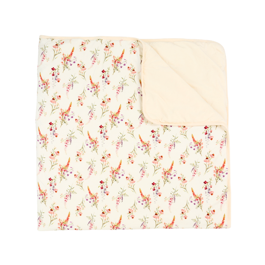 A folded baby blanket featuring a delicate cream floral and bird print on one side and a solid cream reverse side, shown on a plain white background.
