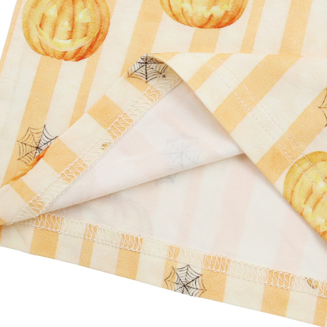 A folded fabric item, likely a baby blanket or cloth napkin, featuring a Halloween theme with orange jack-o'-lanterns, spiderwebs, and a yellow-and-white gingham border on a white background.