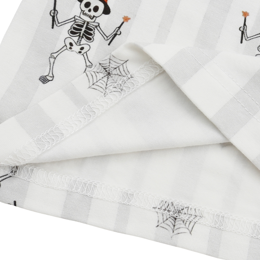 A folded white fabric item, likely a napkin or table linen, featuring a black and white gingham check pattern with printed cartoon skeletons and spiderwebs.