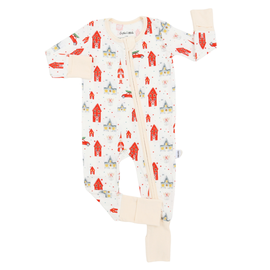 A baby long-sleeve footless zip-up sleeper with a festive winter print of red houses, yellow cars, and blue snow globes on a cream background, featuring beige ribbed cuffs and ankle cuffs.