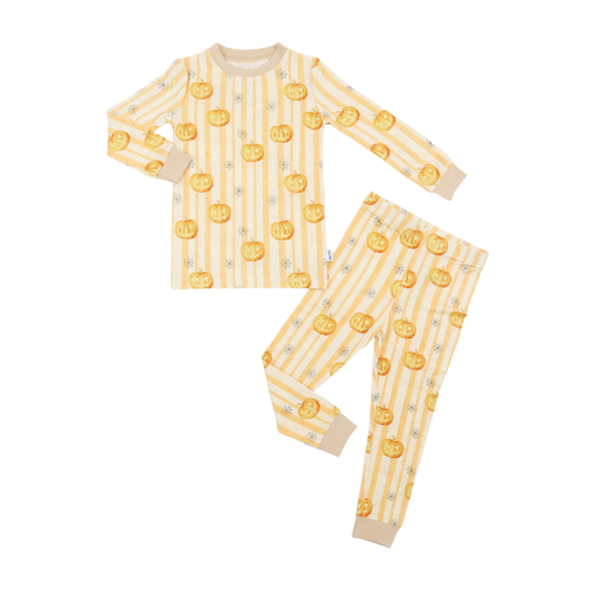 A two-piece children's pajama set featuring a long-sleeve top and matching pants, laid flat on a white background. The pajamas have a cream and pale yellow vertical stripe pattern with a repeating print of orange jack-o'-lantern pumpkins and small gray stars.
