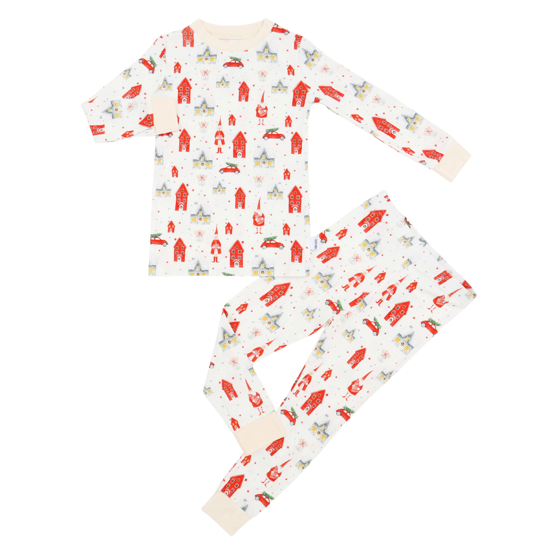 A two-piece children's pajama set laid flat on a white background, featuring a long-sleeve top and matching pants with an all-over print of red houses, blue houses, and small red cars on an off-white base. The cuffs and collar of the top, as well as the leg cuffs, are solid cream.