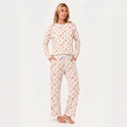 A woman modeling a two-piece long-sleeve pajama set with a cream base and a delicate pink and red floral pattern, featuring a white drawstring waist.