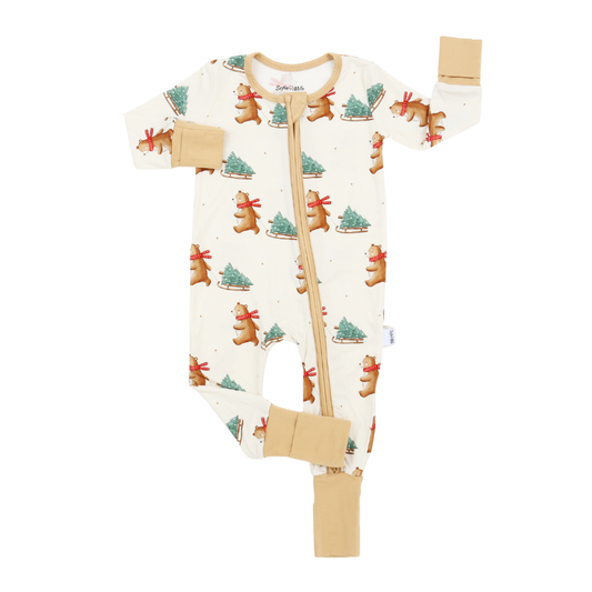 An off-white baby footless one-piece sleeper with a front zipper, featuring a repeating pattern of gingerbread bears and Christmas trees, with tan accents on the cuffs, collar, and zipper trim.