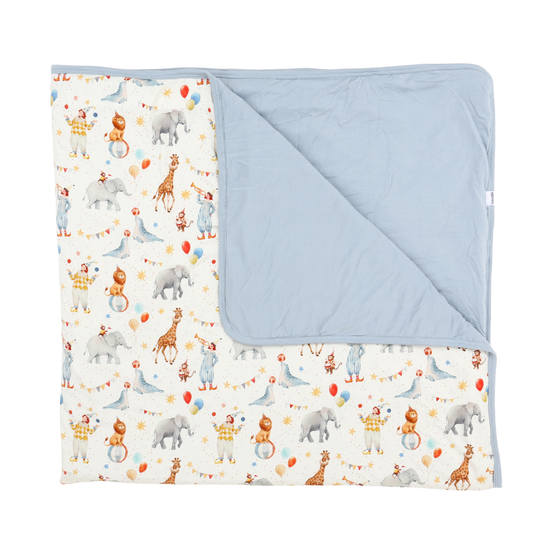 Baby blanket with animal pattern on one side and solid color on the other, displayed against a white background.
