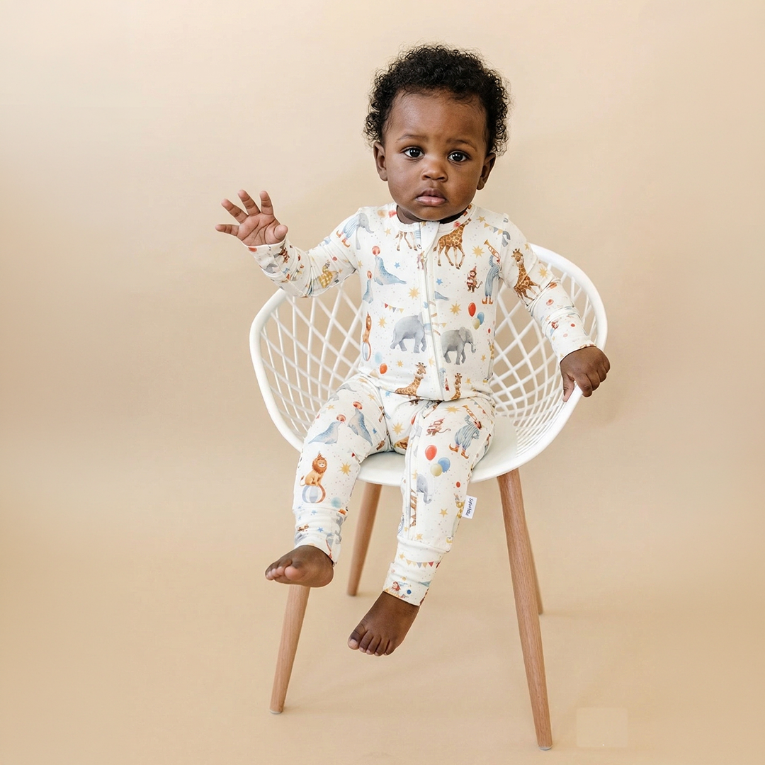 Baby sitting on a small chair wearing a patterned onesie against a beige background