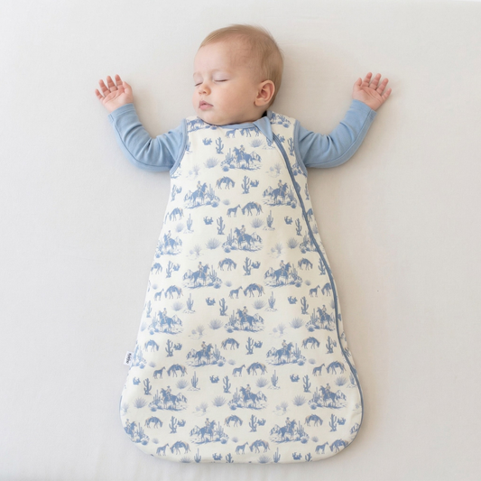Baby sleeping in a blue and white patterned swaddle on a light background