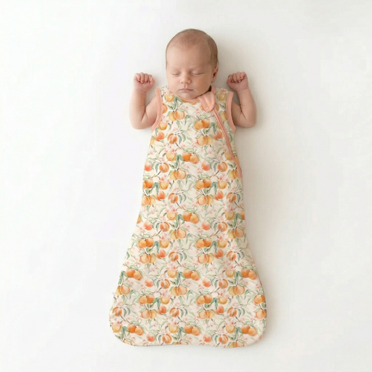 Baby sleeping in a patterned sleep bag on a white background