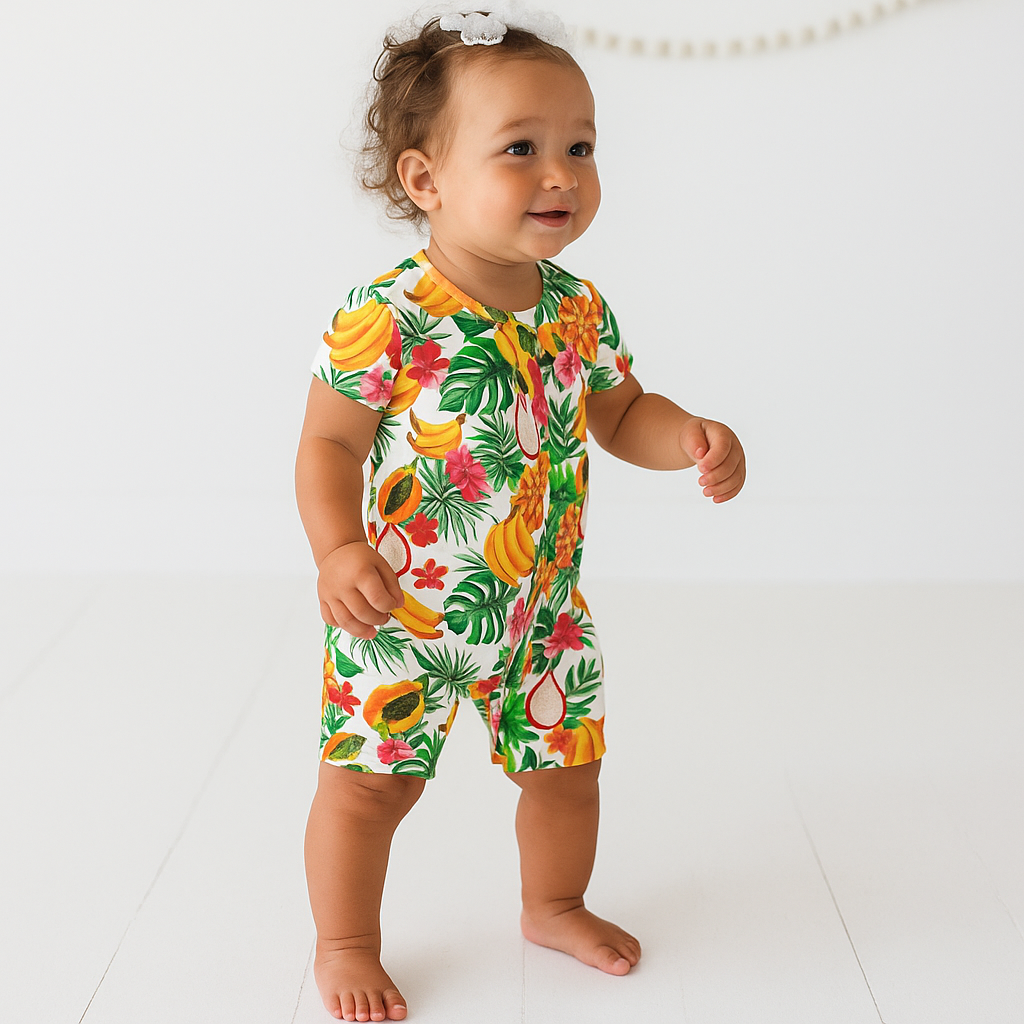 Baby wearing a colorful tropical fruit patterned romper on a white background