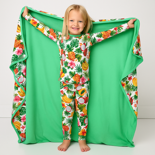 Child wearing a tropical print onesie with a matching green blanket