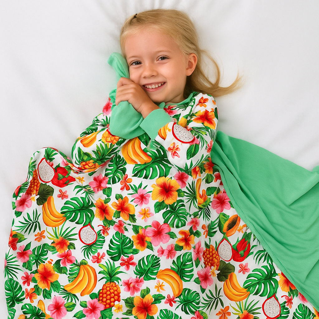 Child wearing a green onesie with a colorful tropical fruit pattern on a white background