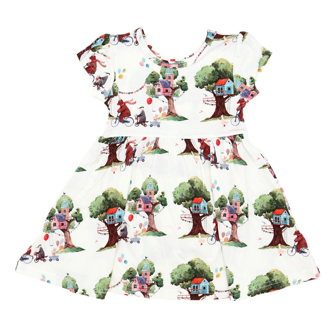 Children's dress with treehouse pattern on a white background