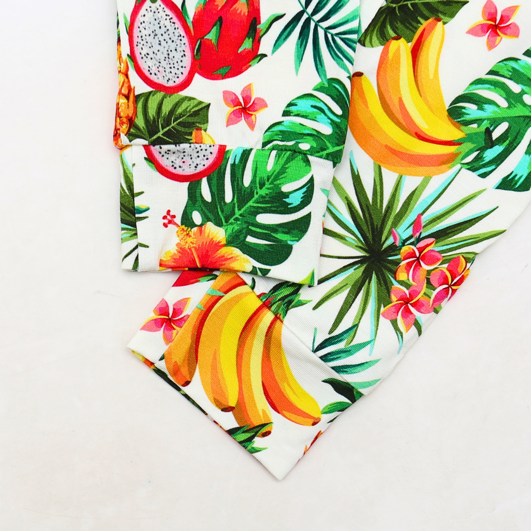 Tropical-themed fabric with bananas, dragon fruit, and flowers on a white background