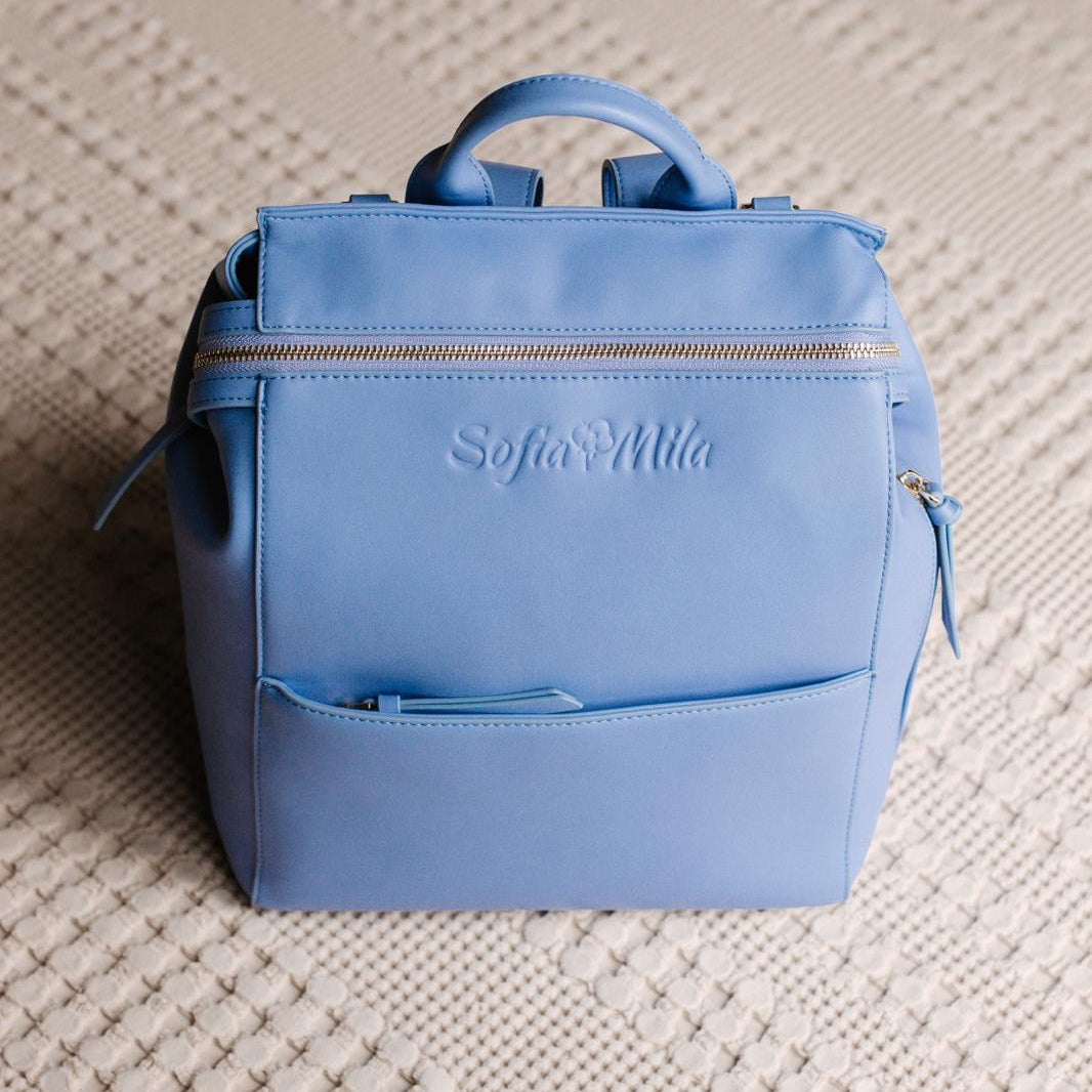 Blue backpack with 'Sofia Mila' branding on a textured surface