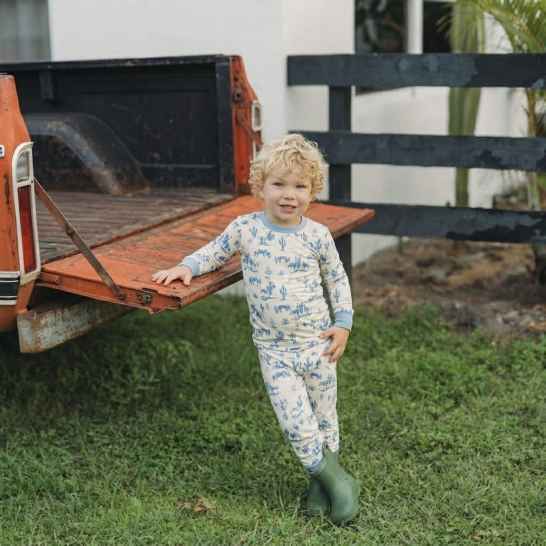 Child in pajamas standing next to a vintage truck on grass