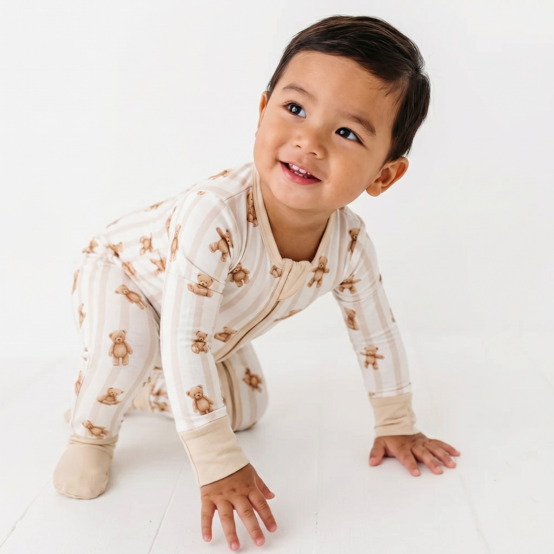 Child wearing a beige onesie with teddy bear pattern on a white background