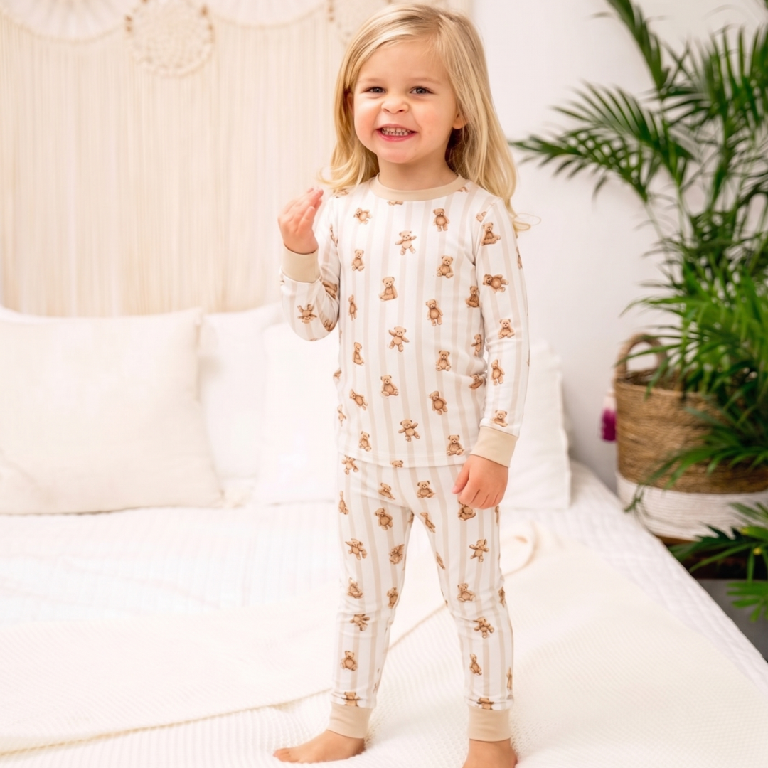 Child wearing a white pajama set with gold patterns in a cozy room.