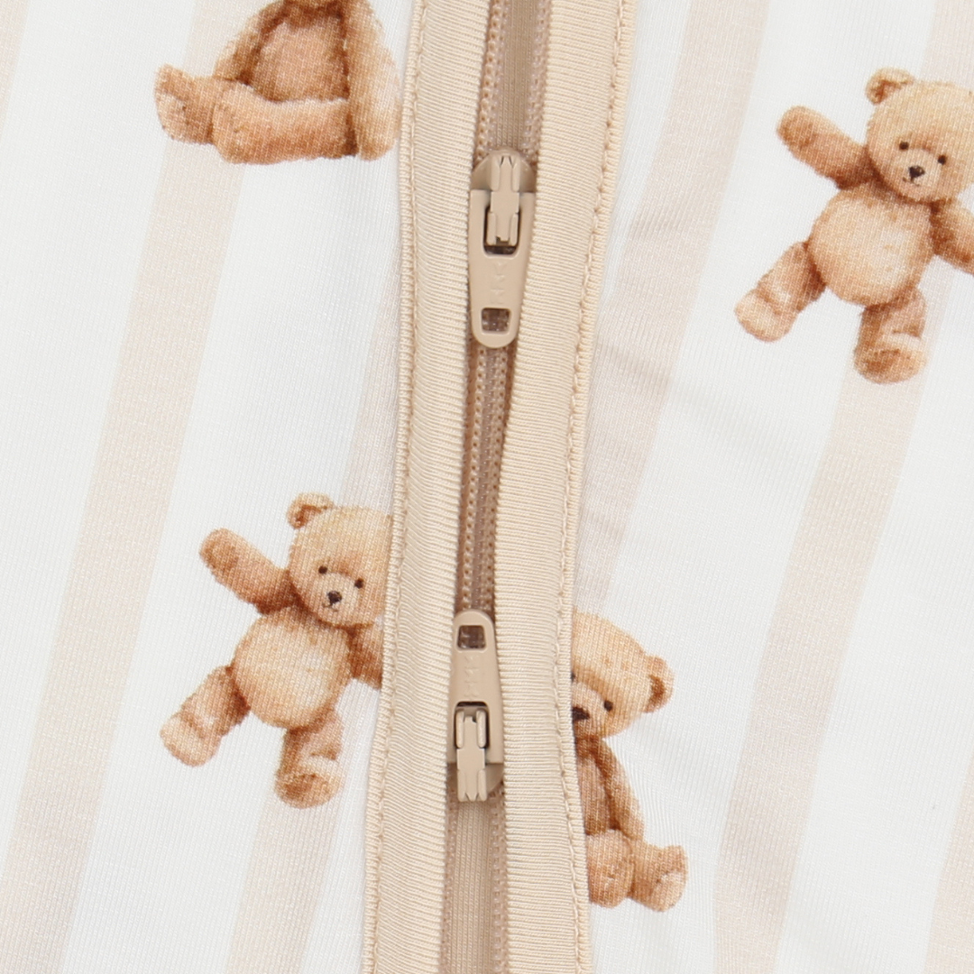 Close-up of a beige zipper with teddy bear patterns on a light background