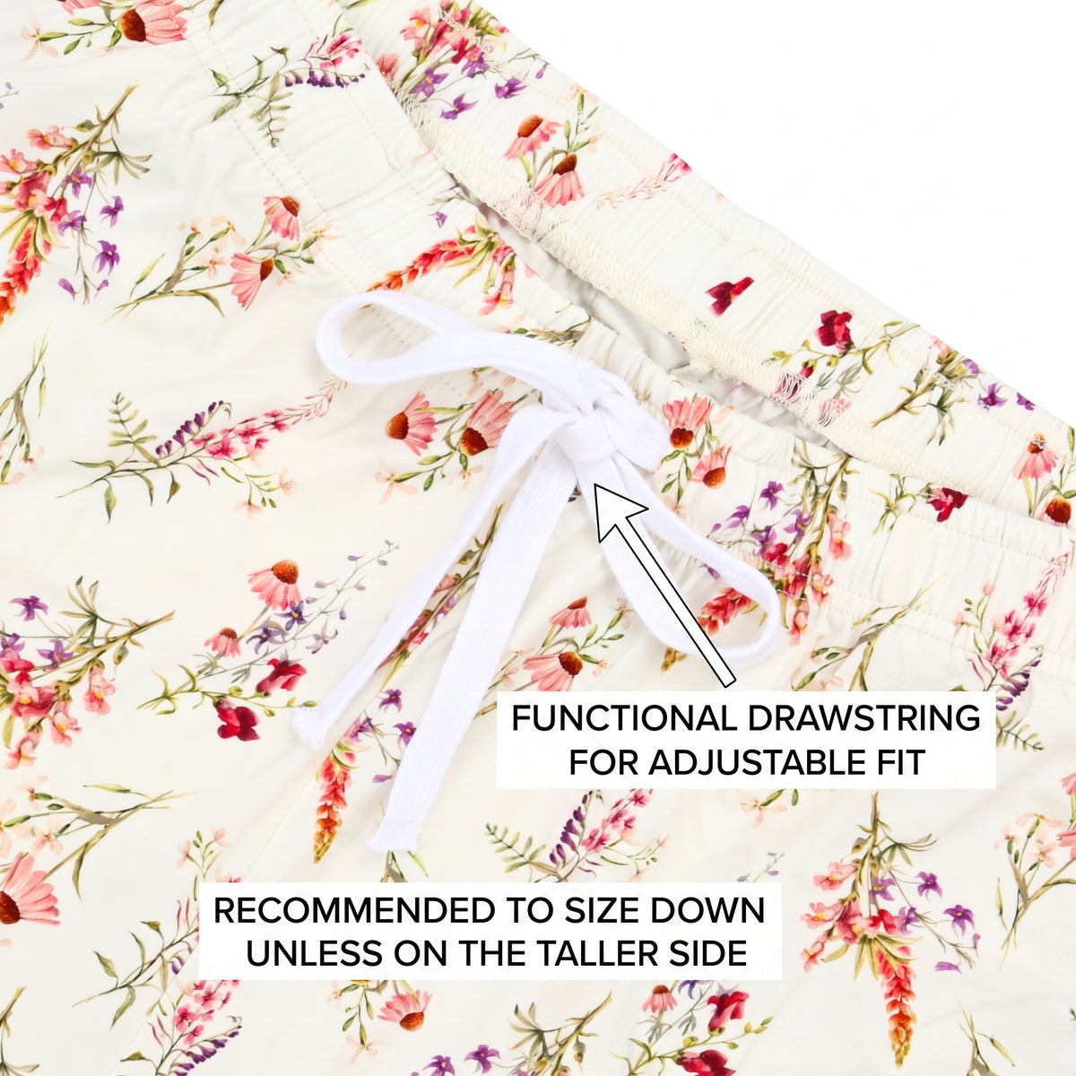 Close-up of a floral drawstring waistband, showing an elasticized cream fabric with pink, red, and purple flowers and green stems, plus a white drawstring tied in a bow. Text overlays explain the functional drawstring and sizing recommendation.