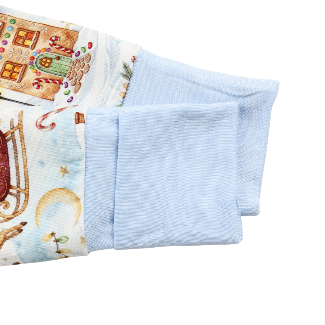Close-up of a light blue knit fabric cuff folded over to show the interior, next to a printed fabric section with a gingerbread house and holiday scene.