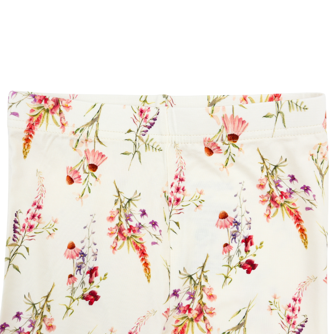 Close-up of a white garment with a colorful floral print featuring pink, red, purple, and orange flowers with green stems.