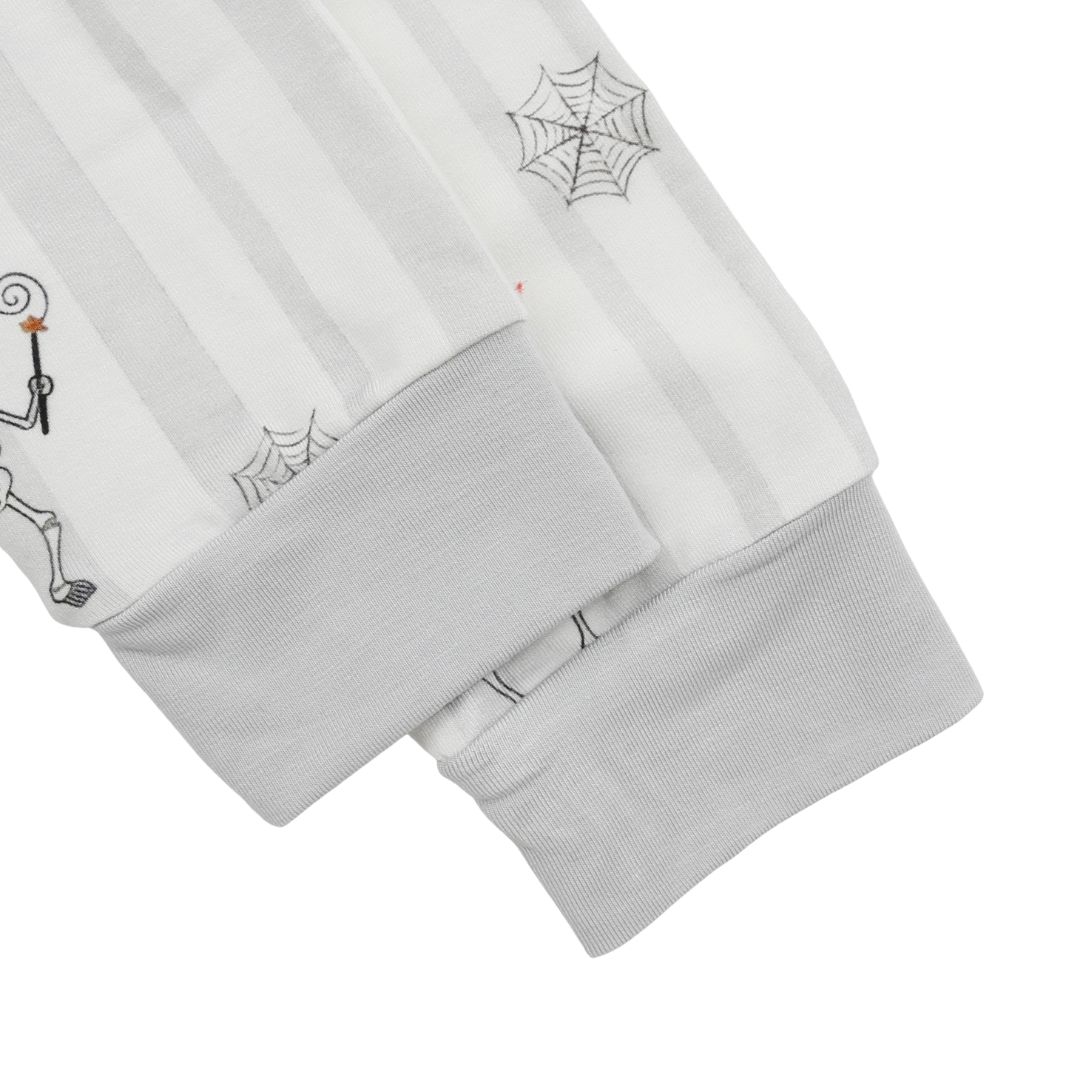 Close-up of a white striped long-sleeve garment with gray ribbed cuffs and printed spiderweb and skeleton graphics on a white background.