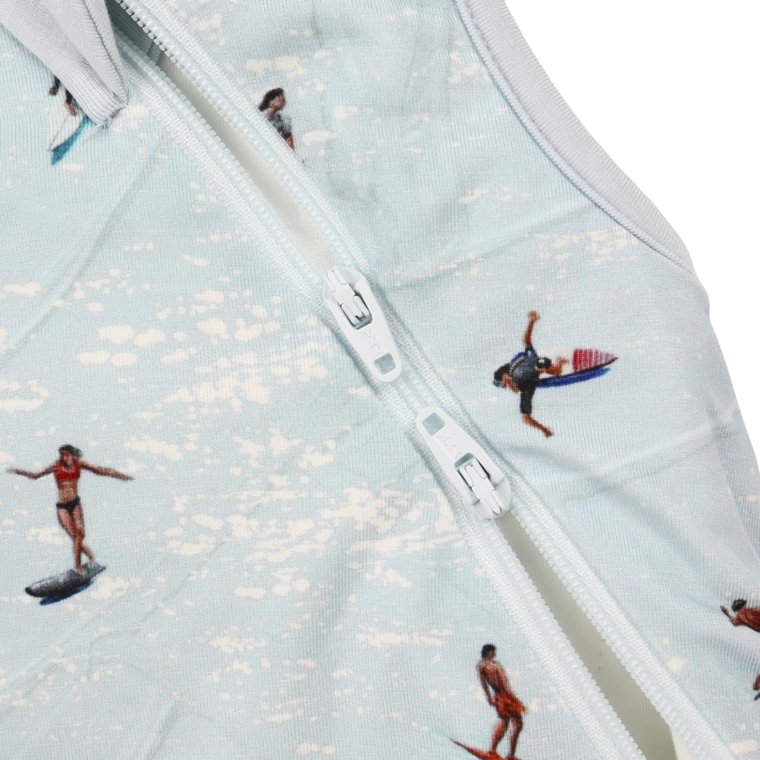 Close-up of a zipper with small figures of people on surfboards and a boat.
