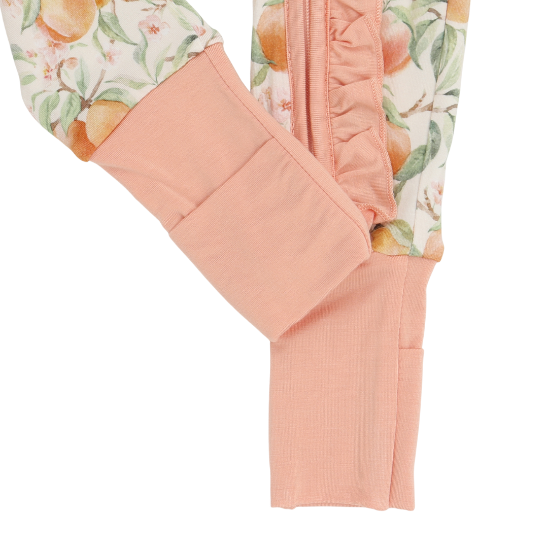 Close-up of peach-colored pants with floral patterned waistband on a white background