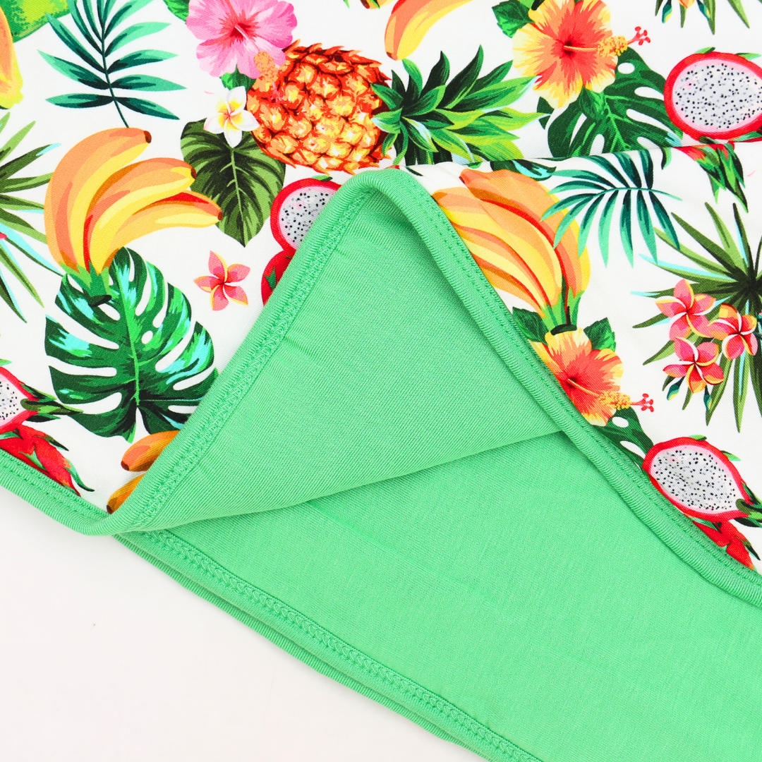 Green fabric with a tropical fruit and leaf pattern on a white background