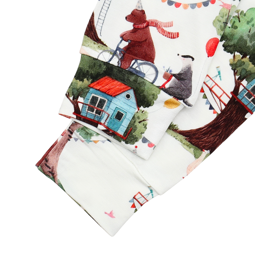 Fabric with a colorful print of a bear, house, and trees on a white background