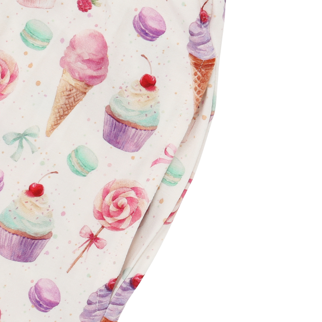 Leggings with a colorful pattern of ice cream cones, cupcakes, and lollipops on a white background.