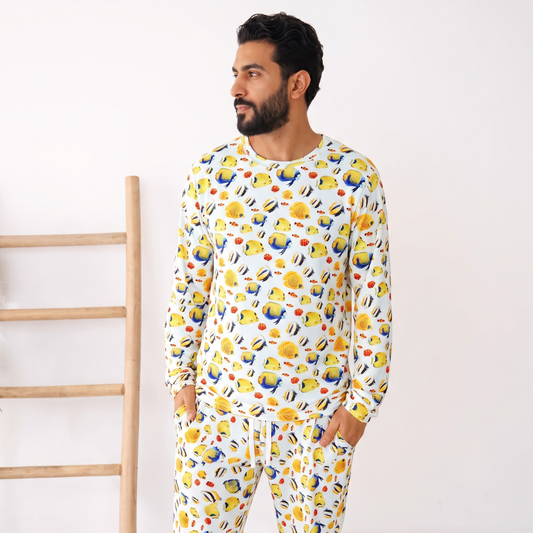 Man wearing a colorful onesie with a pattern of cartoon characters against a white background.