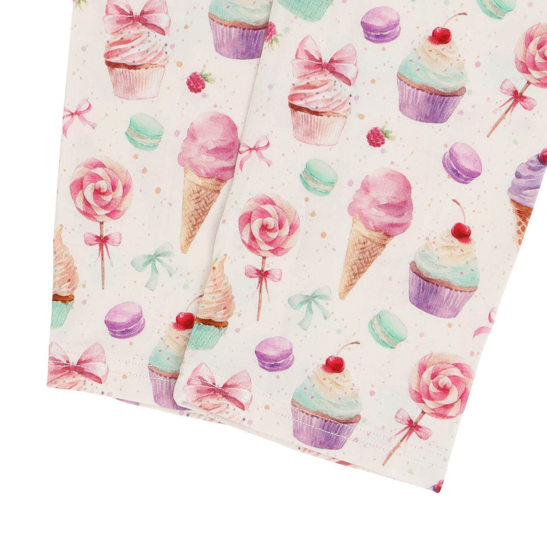 Two fabric swatches with a colorful pattern of ice cream cones, cupcakes, and lollipops on a white background.