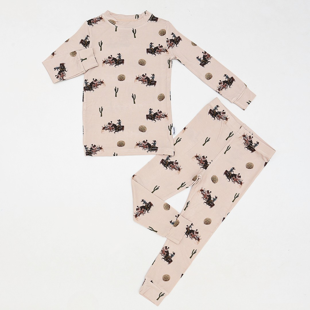 Kids 2-piece bamboo pajamas with western rodeo print featuring cowboys, cacti, and tumbleweeds on a beige background – soft breathable sleepwear for toddlers and children.